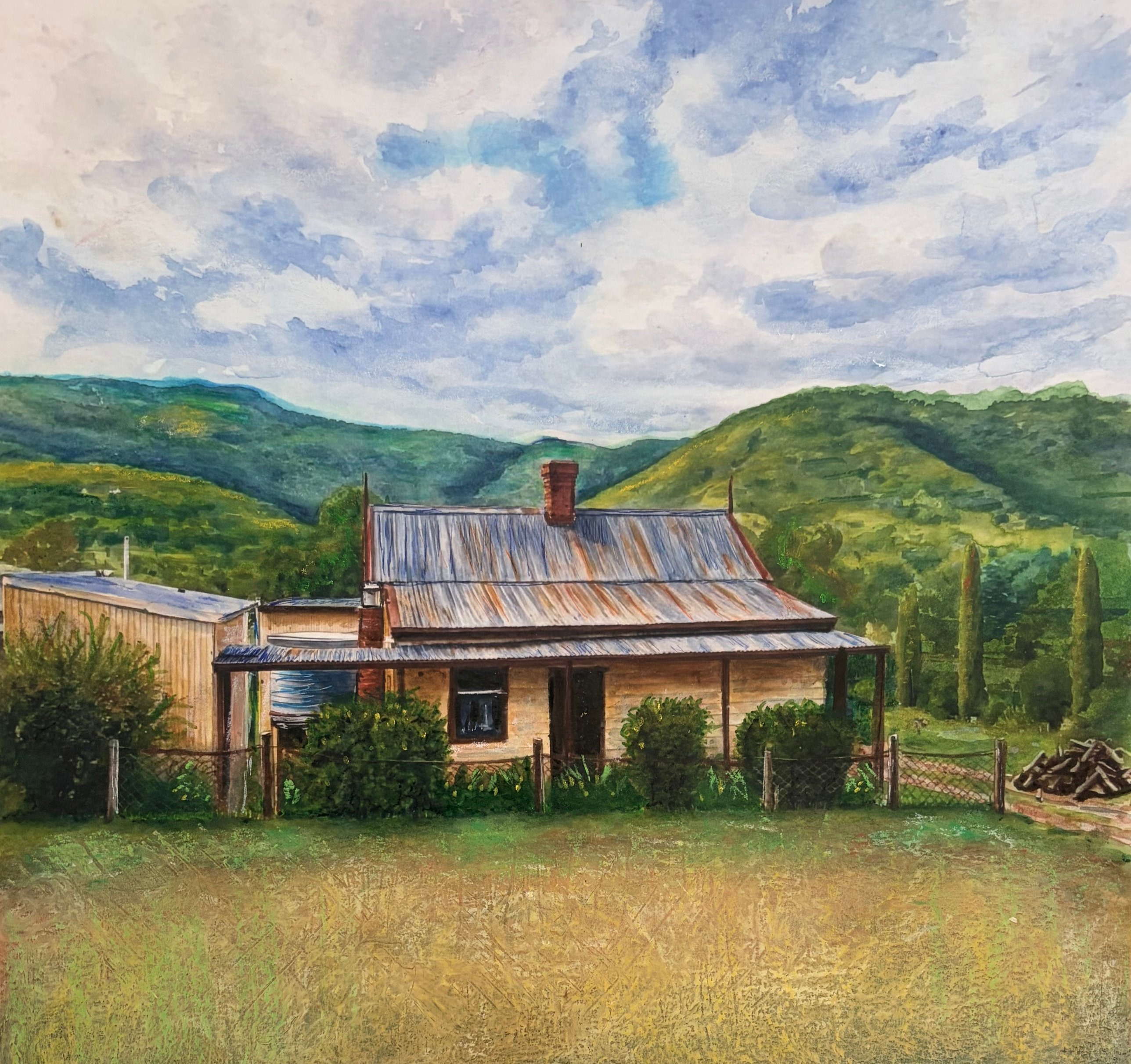 Old tin-roofed cottage with woodpile and green hills
